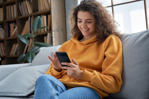 Picture of smiling girl using mobile phone at home